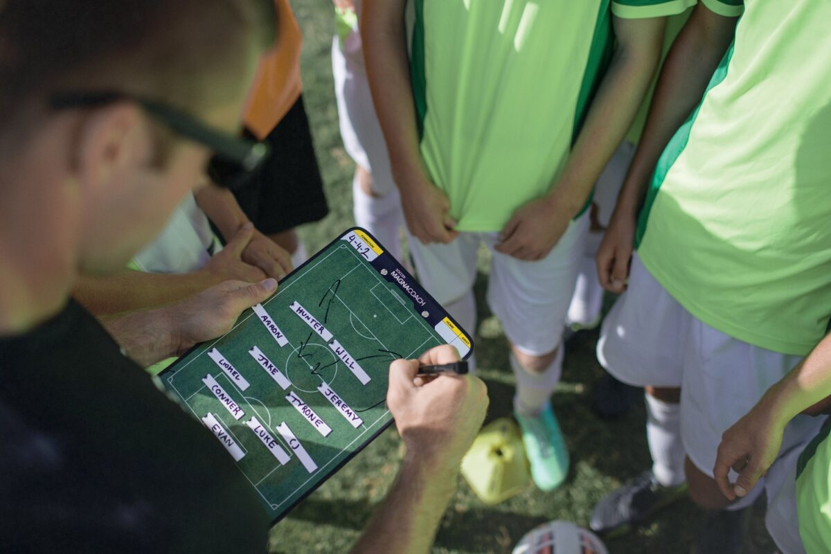 מאמן מסביר לקבוצה מהלכים על לוח טקטי למאמן כדורגל - MagnaCoach Soccer