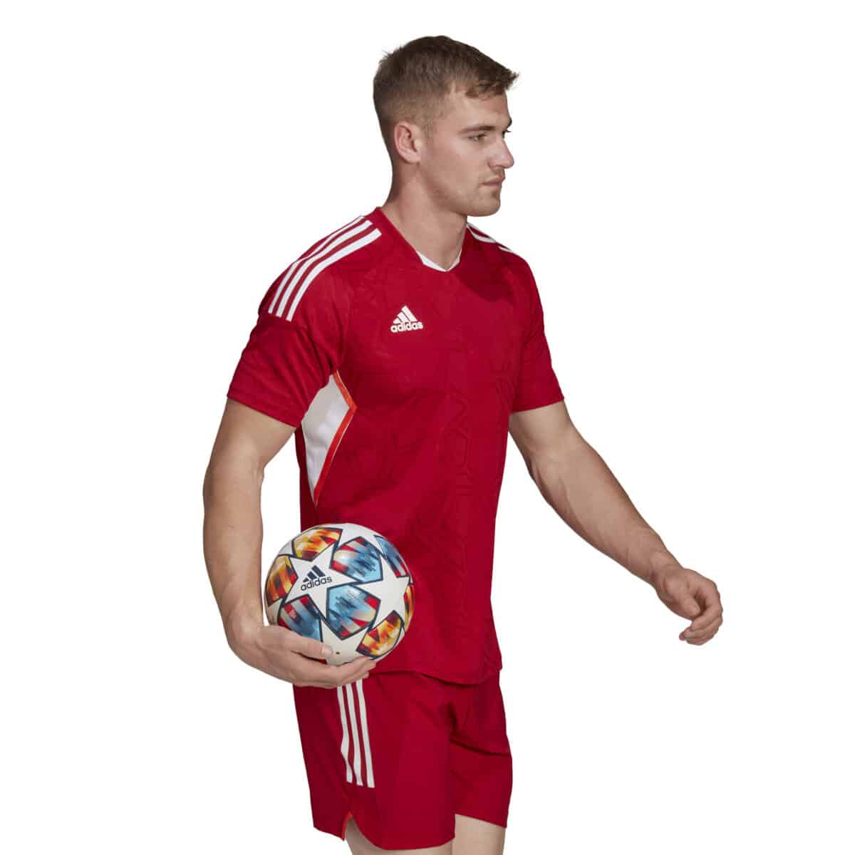 חולצת משחק אדומה Adidas Condivo 22 על כדורגלן תמונה מצד ימין חצי גוף ביד ימין כדור כדורגל אדידס