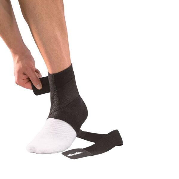 Neoprene Ankle Support With Strap - מגן קרסול לתמיכה של Mueller פתוח עם רצועה וסקוץ' על רגל שמאל של גבר עם גרב לבנה