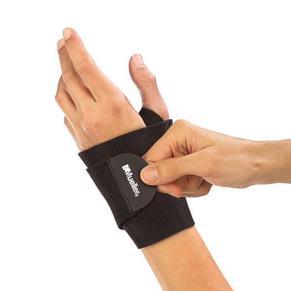 Wrist Support Wrap - תומך כף יד מניאופראן של Mueller בצבע שחור מבית מולר על יד שמאל של גבר שמחזק את הסגירה של המגן ביד ימין