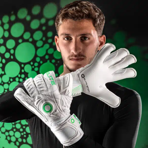 כפפות שוער Elite Squid על הידיים של שוער כדורגל שתופס את יד שמאל שלו עם יד ימין מול הפנים על רקע כתמי דיו