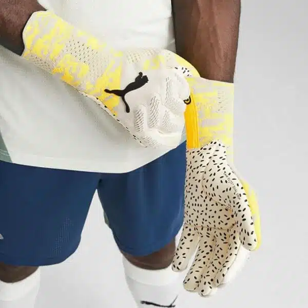 כפפות שוער Puma Future Ultimate NC White על ידיים של שוער אפרו. זום אין רק על הידיים כאשר יד ימין מושכת את הכפפה ביד שמאל כלפי מעלה